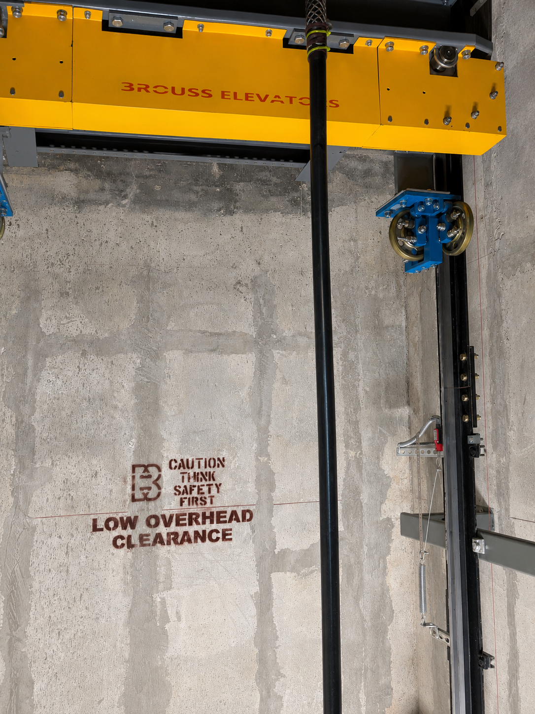Elevator car top crosshead branded Brouss Elevators with blue sheave in the hoistway at Clima Home