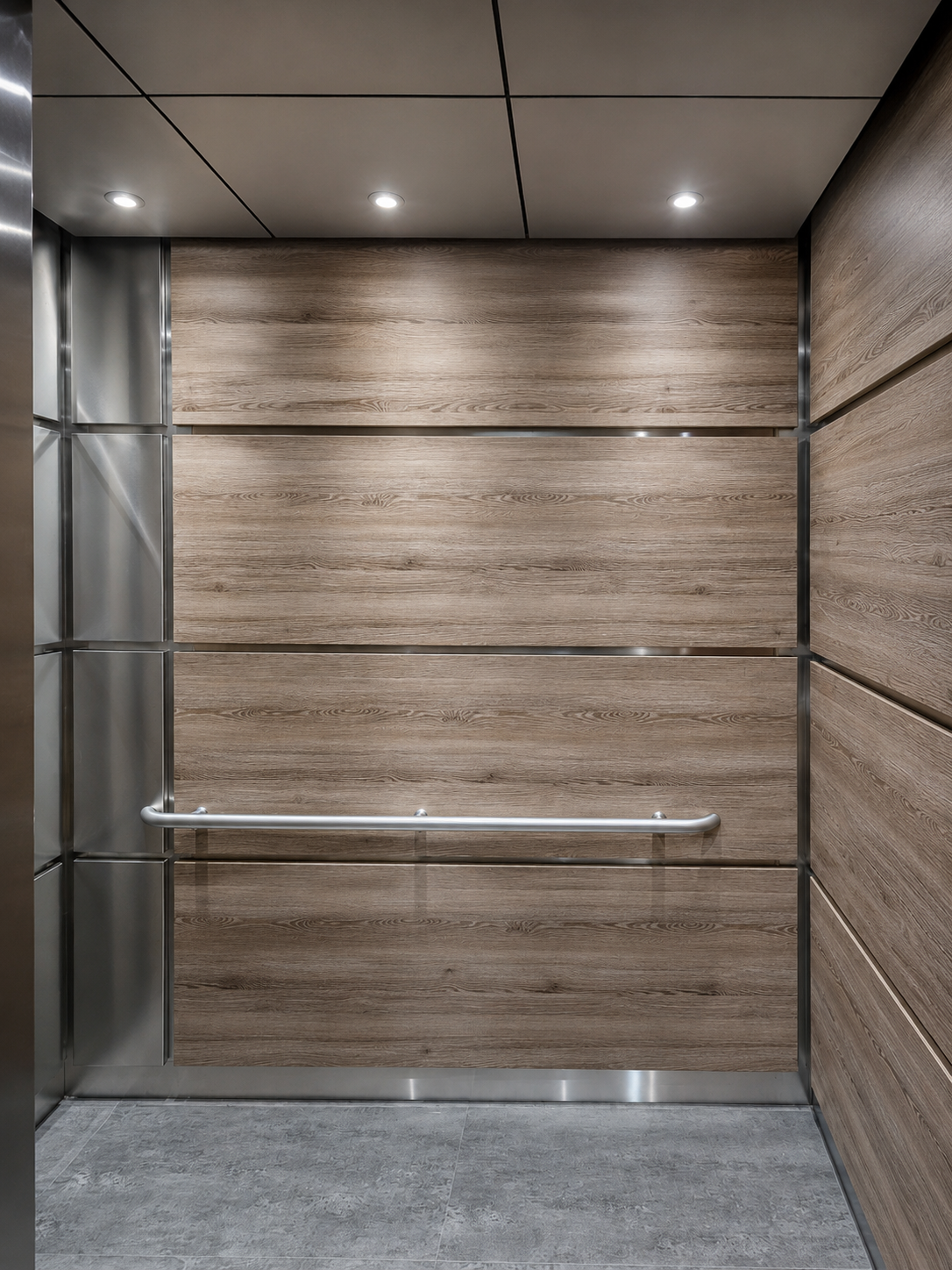 Elevator cab with warm wood laminate panels, stainless steel trim, handrail and gray tile floor at Univida Medical Center in Hialeah