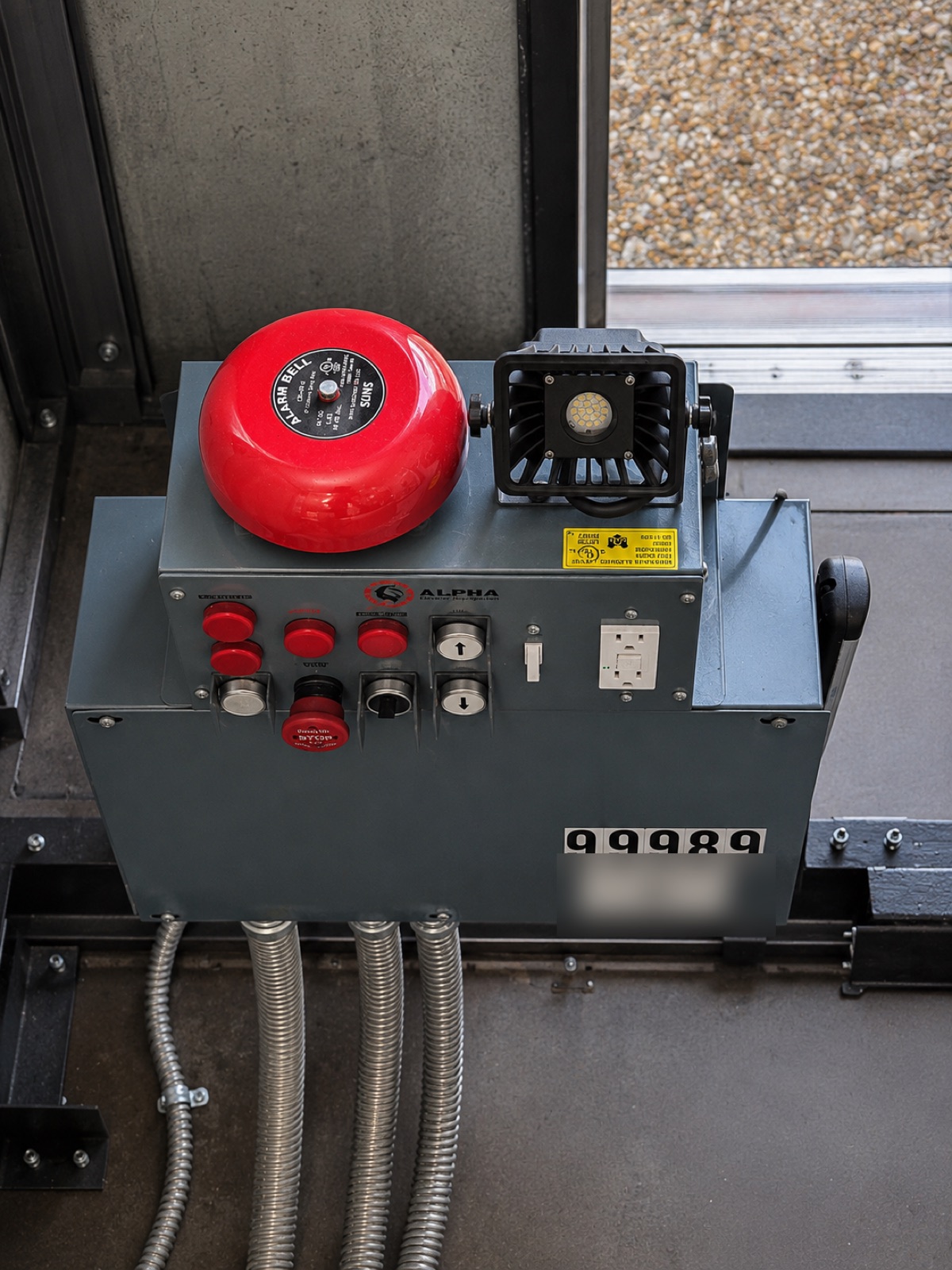 Elevator car top with red alarm bell, strobe light and Alpha control station showing the state ID number at Flagler Wood in Miami
