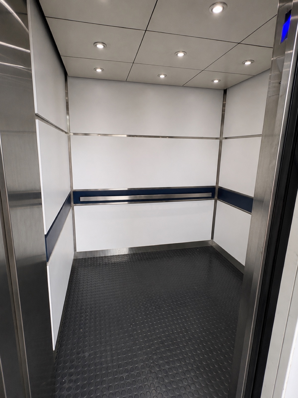 New elevator cab interior with white panels, a blue accent stripe and stainless trim at Doral Place 87