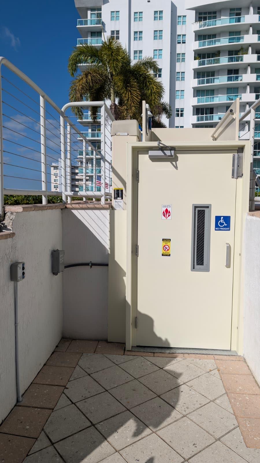 Ground floor landing door of the ADA platform lift with accessibility signage at North Bay Village