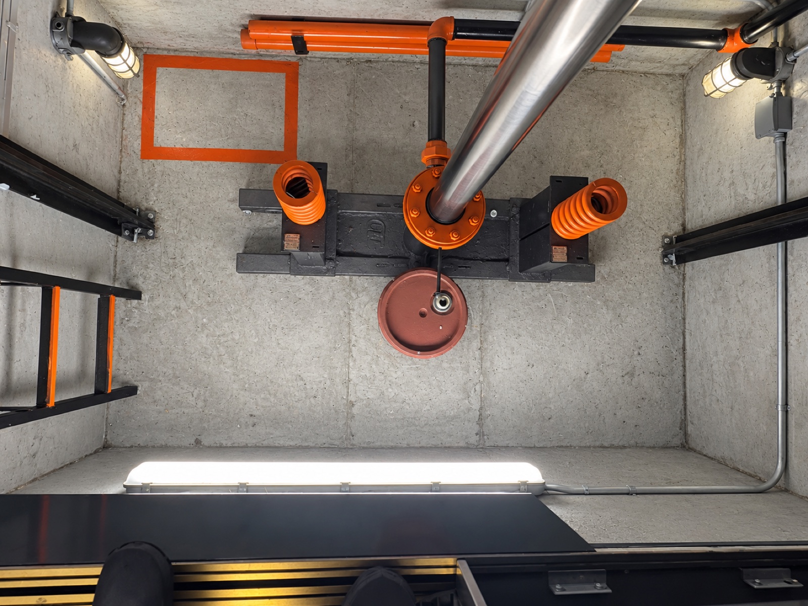 Elevator pit at Milam 25 in Miami, with the jack assembly, orange buffer springs and pit ladder after a Brouss Elevators maintenance visit