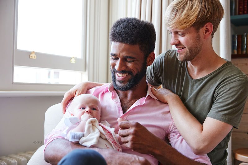 Male same-sex couple holding their new baby.