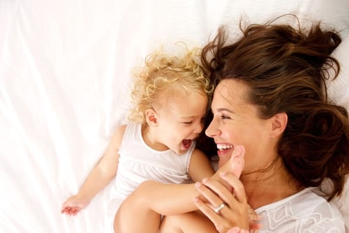 view portrait of happy mother and daughter lying on bed at home-img-blog