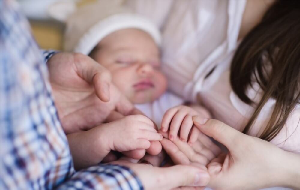 mother and father holding a baby after being born through IVF treatment