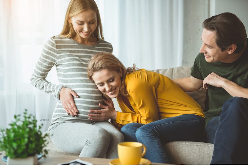 Surrogate allows intended parents to feel her tummy.