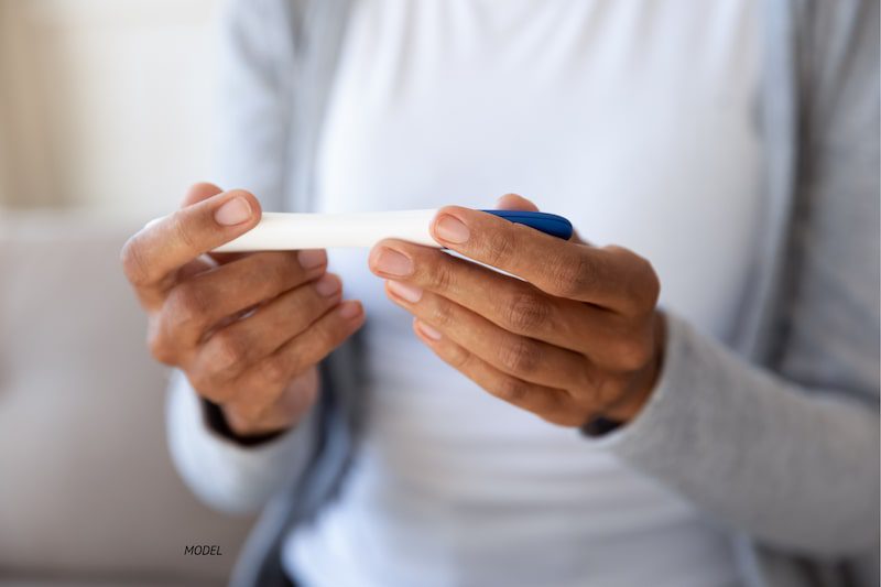 Close-up of woman's hands holding a pregnancy test.
