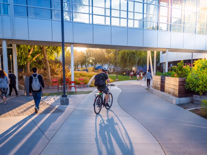 student cycing across college campus
