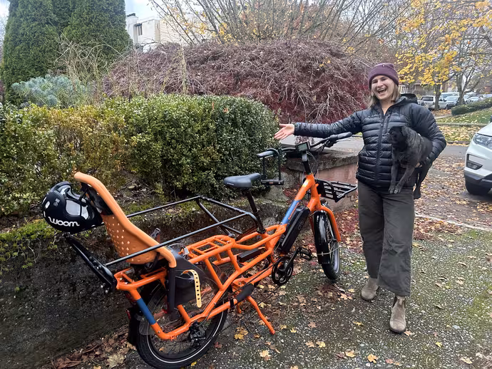 Mckenzie Becker's partner holding the family pug and standing beside the cargo -e-bike they recovered with the help of 529 Detective