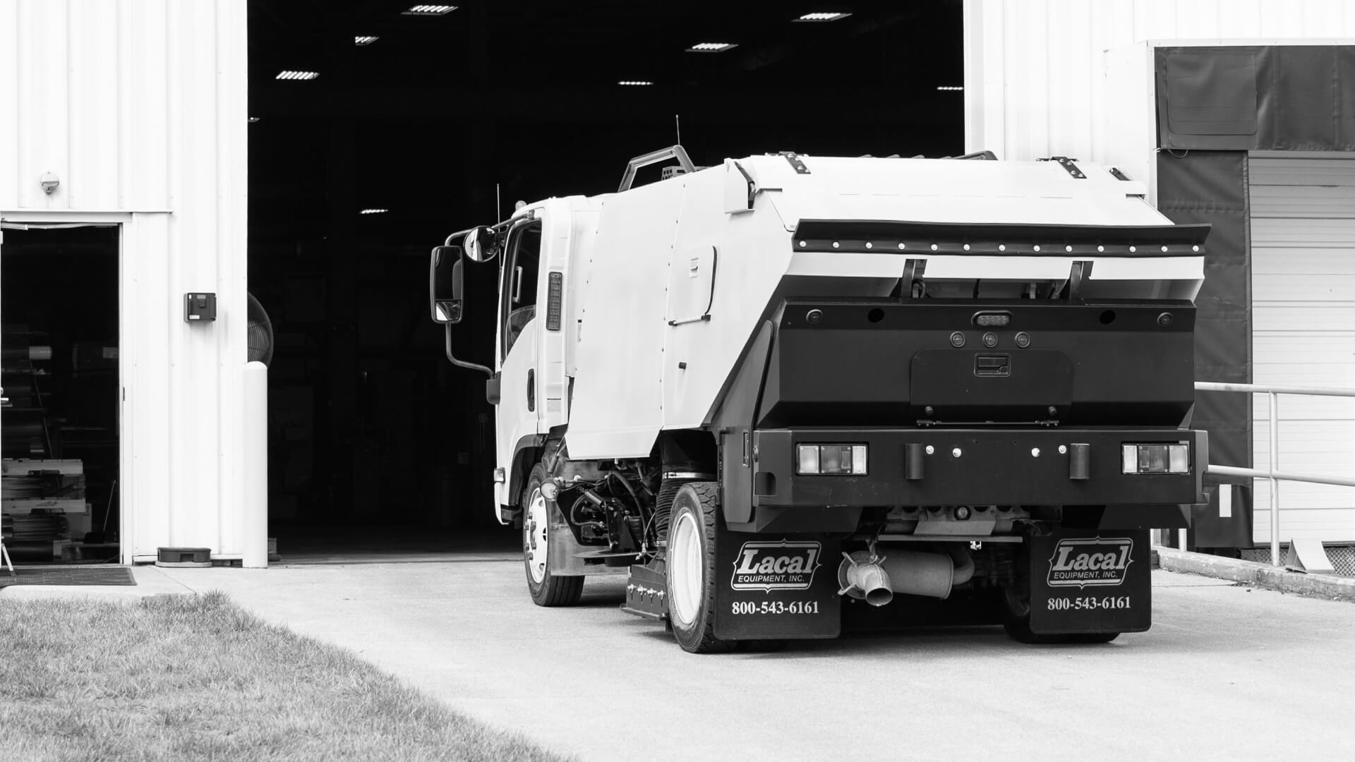 Reconditioned street sweeper truck outside a building with Lacal Equipment branding.