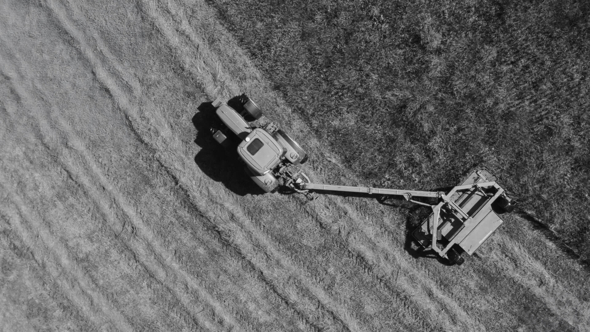 Tractor pulling rotary mower in field.