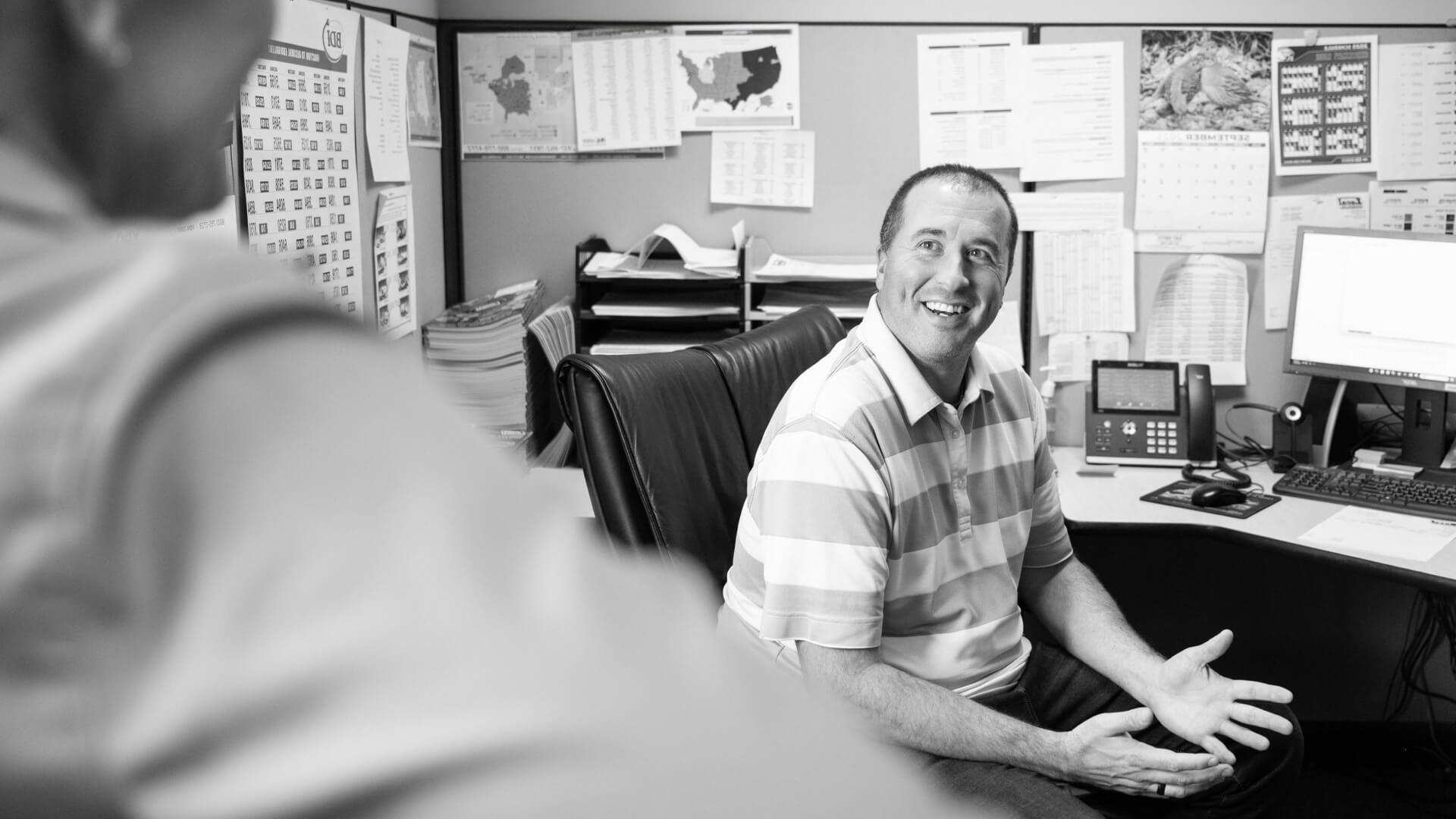 Man smiling and talking in office.