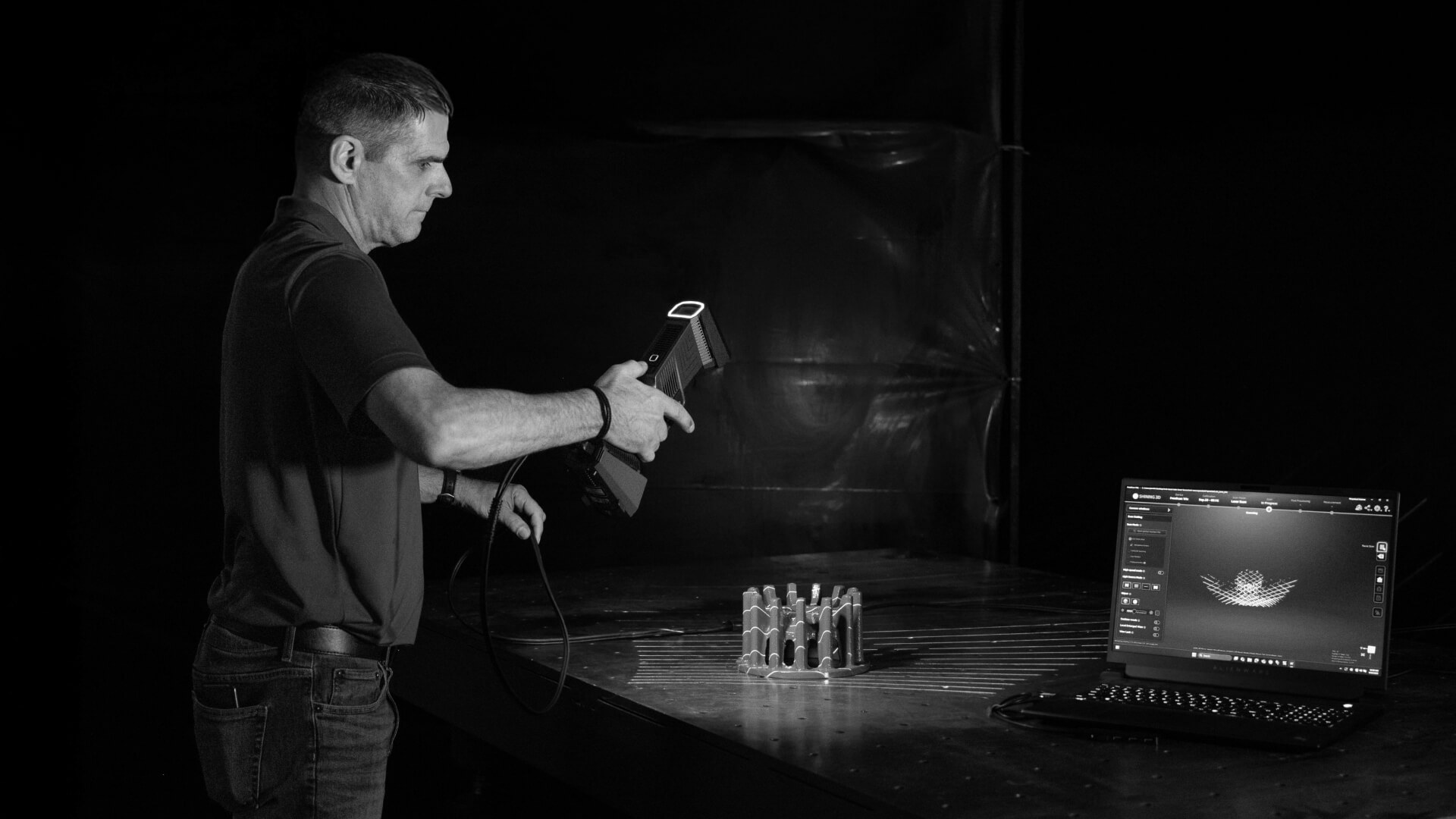 Man using a laser to scan replacement part with laptop open and screen showcasing the scanned part.
