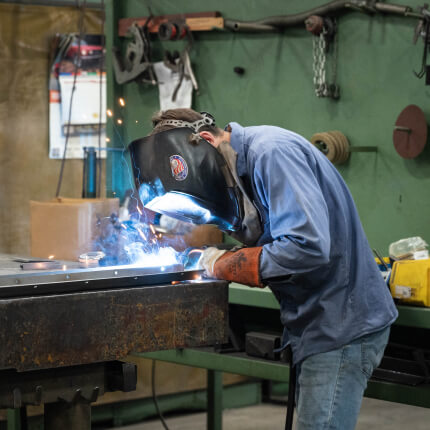 Worker welding metal in workshop.