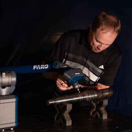 Worker using Quantum X FaroArm® to scan part. 