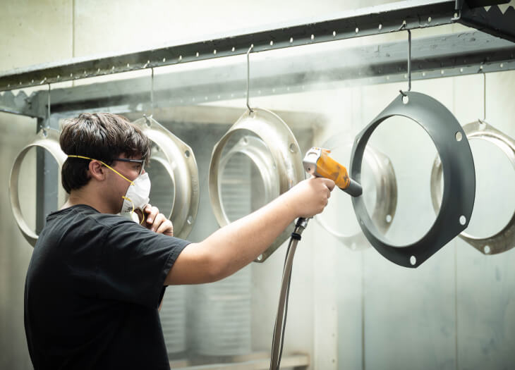Worker powder coating metal parts.