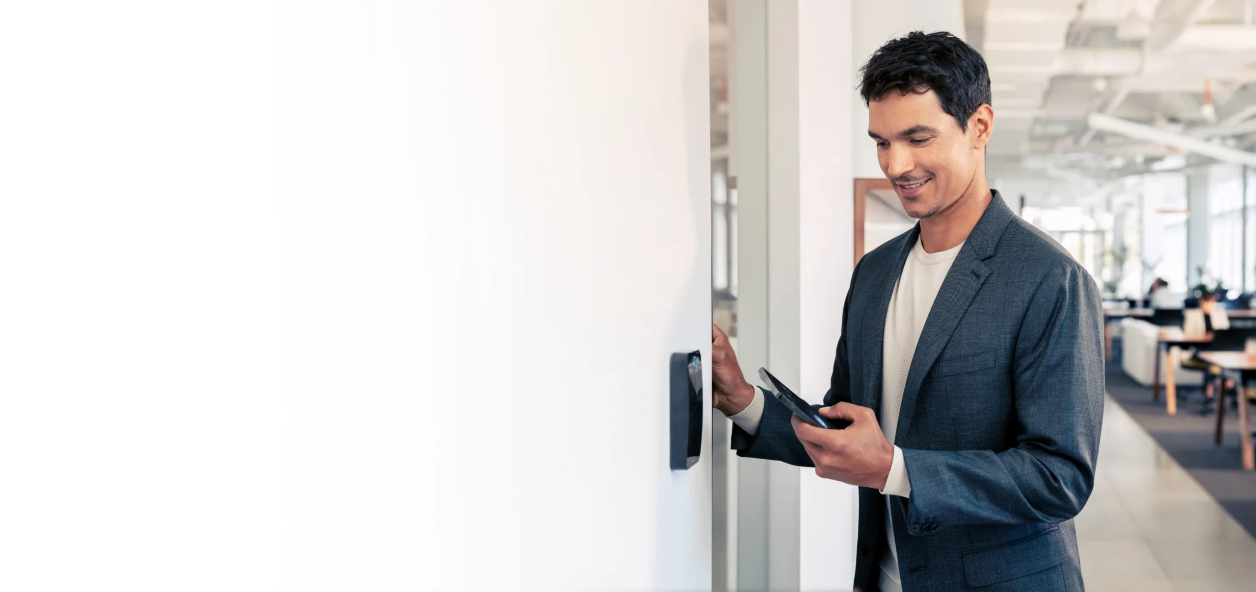 Business professional using mobile credentials to unlock a smart access control reader inside a modern office.
