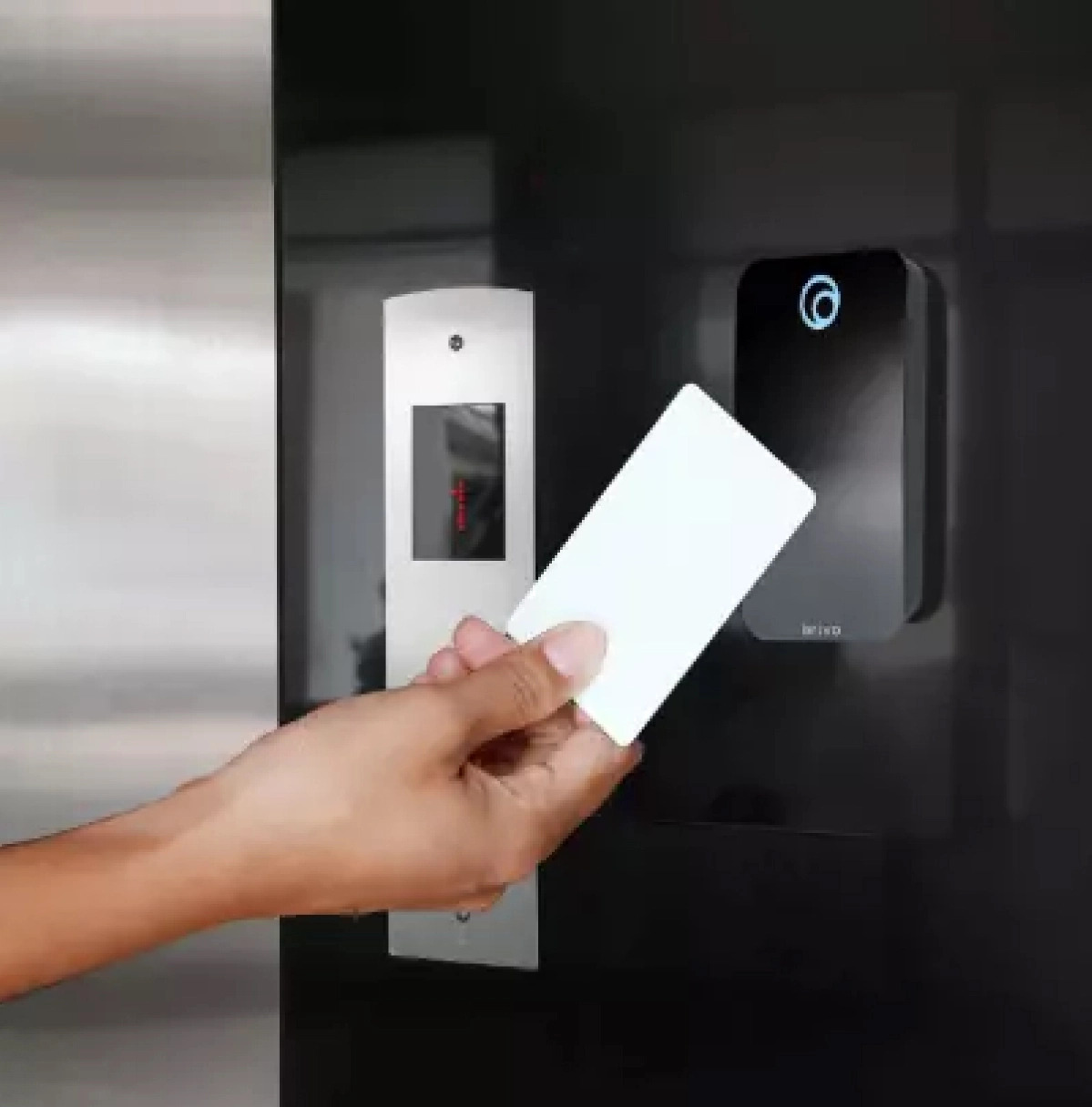 Close-up of a person using a key card with a Brivo access control reader to unlock a secure door.