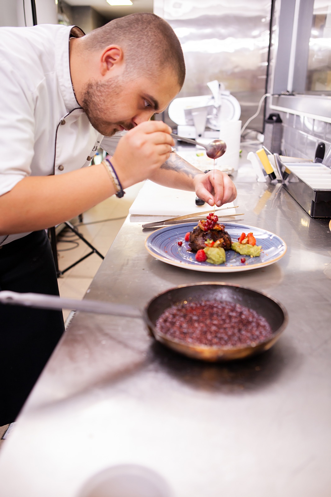 A chef plating a dish in a restaurant kitchen.