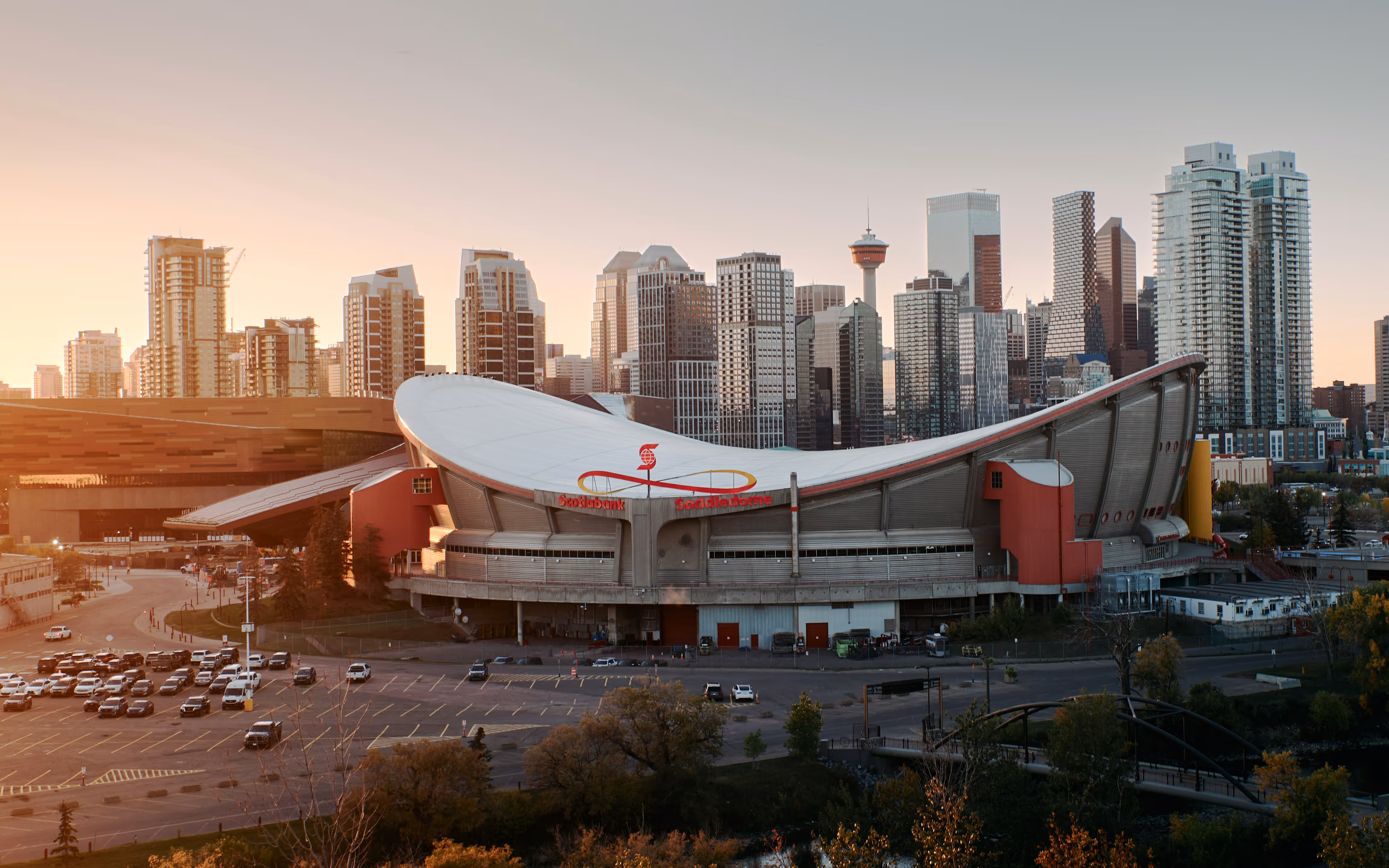 Scotiabank Saddledome arena with Calgary city skyline at sunset in the background.