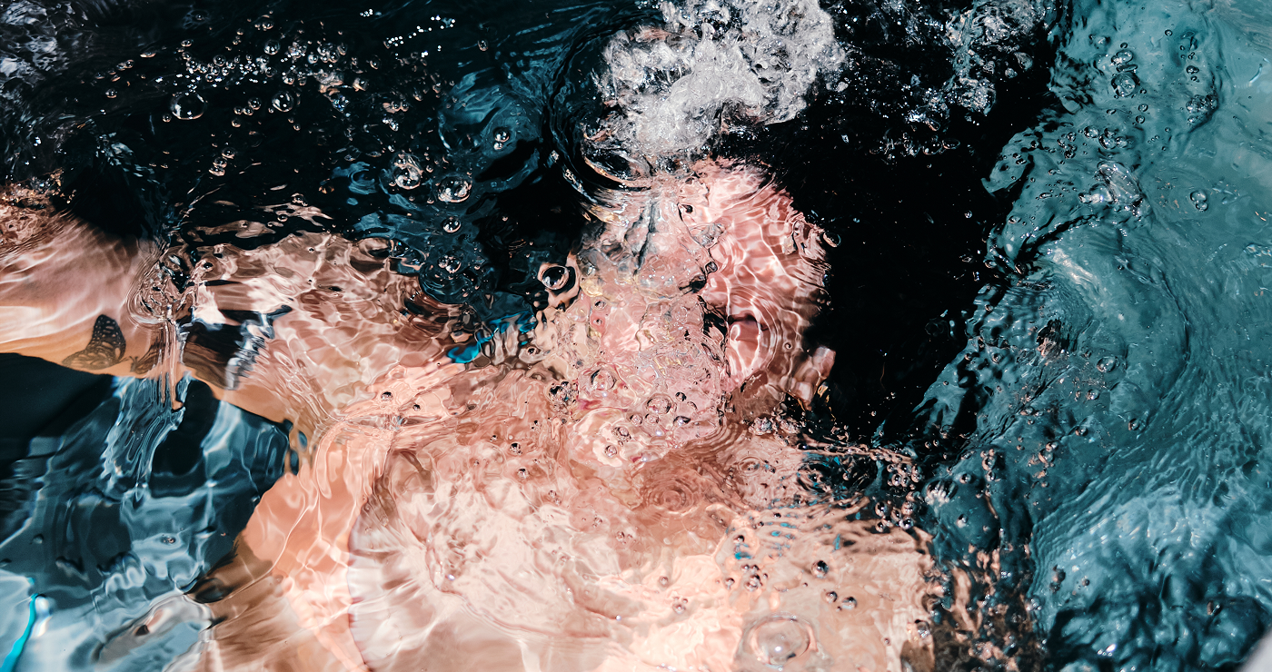 Person submerged underwater with bubbles and light reflections distorting the view.