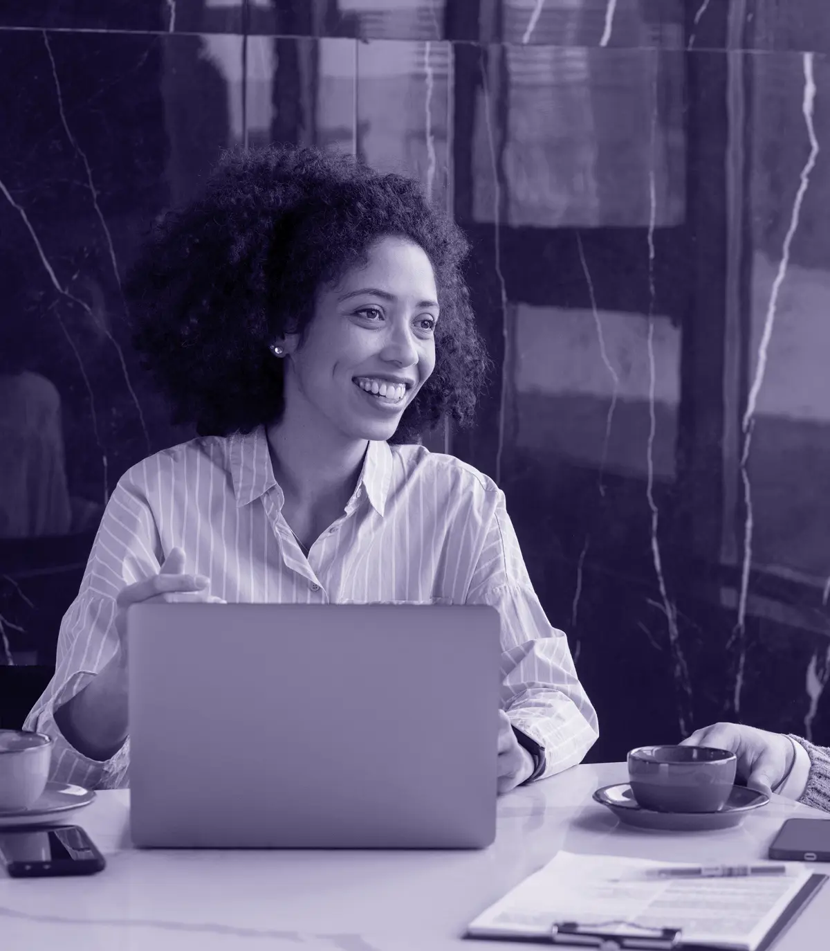 Woman smiling while working on a laptop in a meeting room.