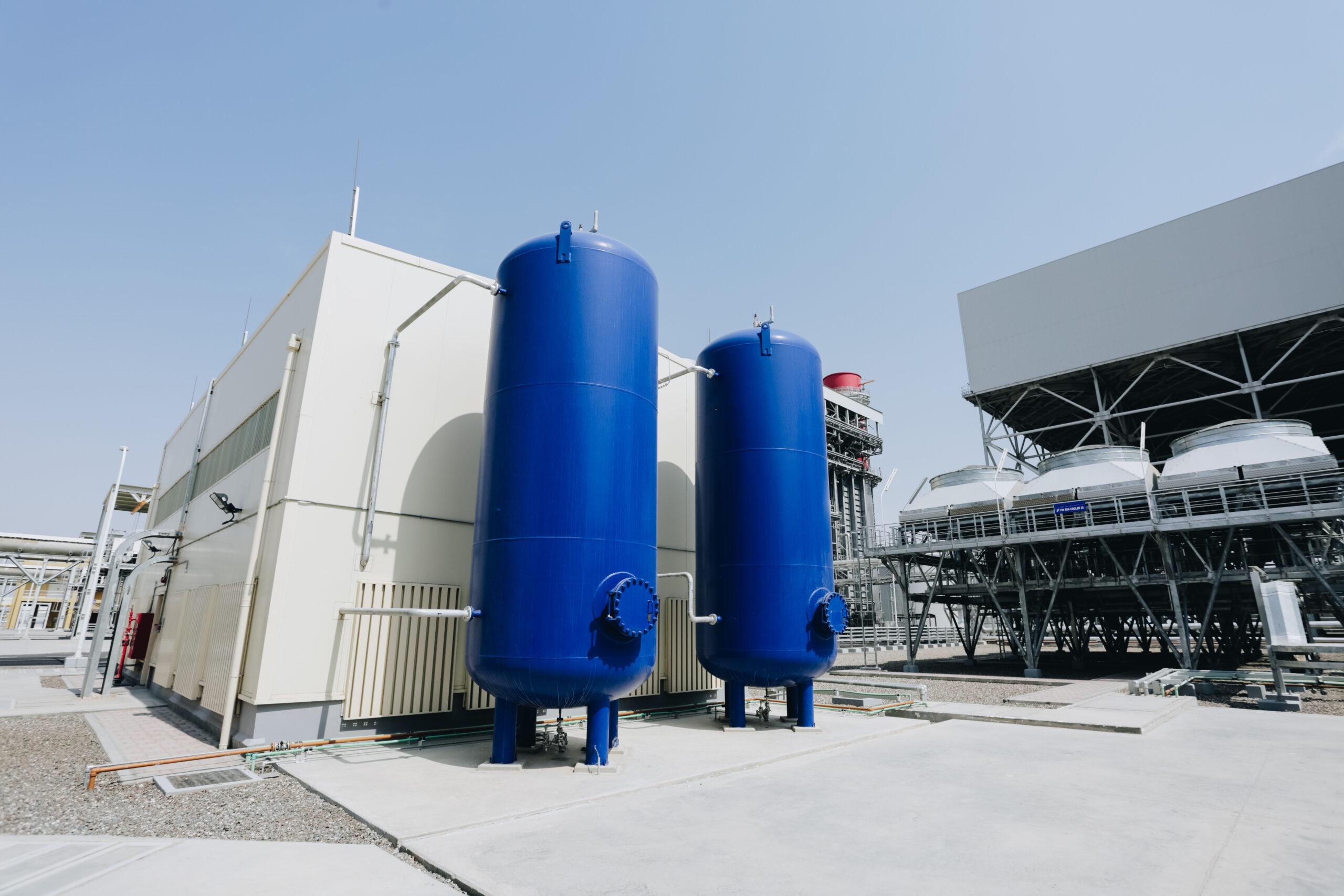 Engineers inspecting a hydrogen backup power system at a modern data center with hydrogen storage tanks, monitoring equipment, and safety control systems.