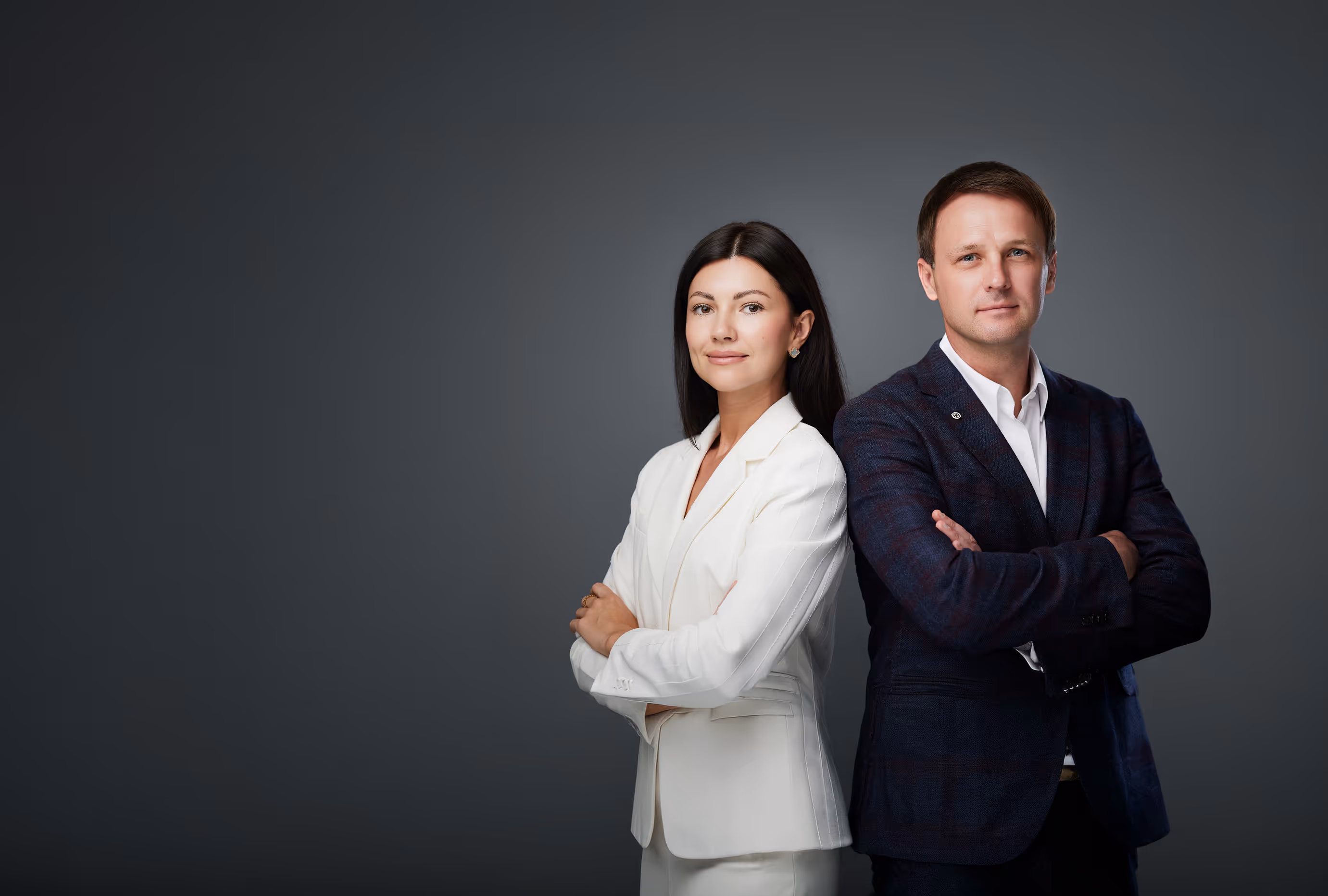 Agency founders Anna and Mikhail Bushmin standing back-to-back with crossed arms against a dark gray background