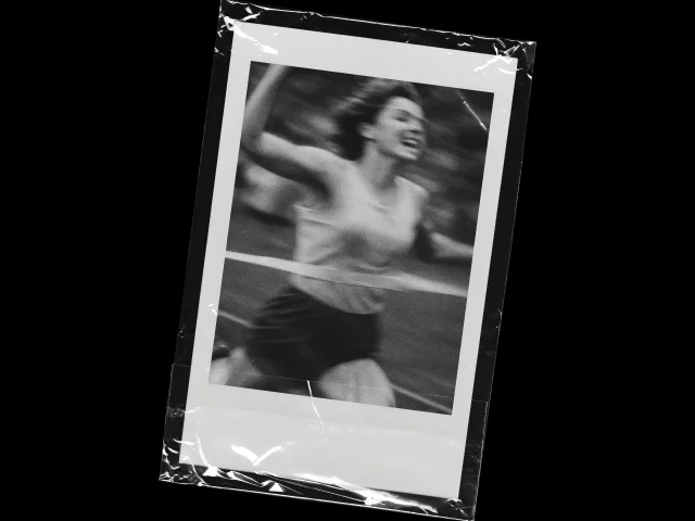 Black and white photo of a woman runner crossing the finish line, taped like a Polaroid picture.