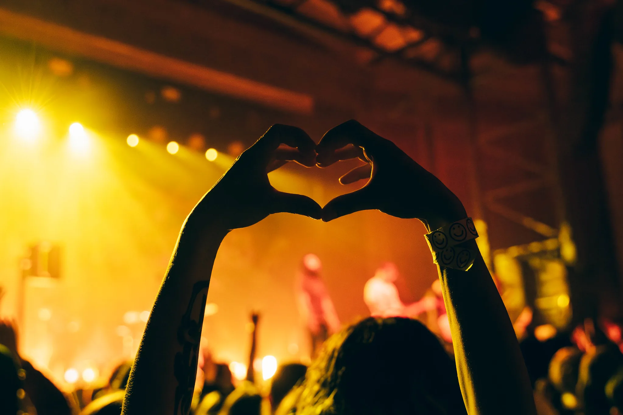 Fans making heart shapes with their hands at a show at The UC Theatre