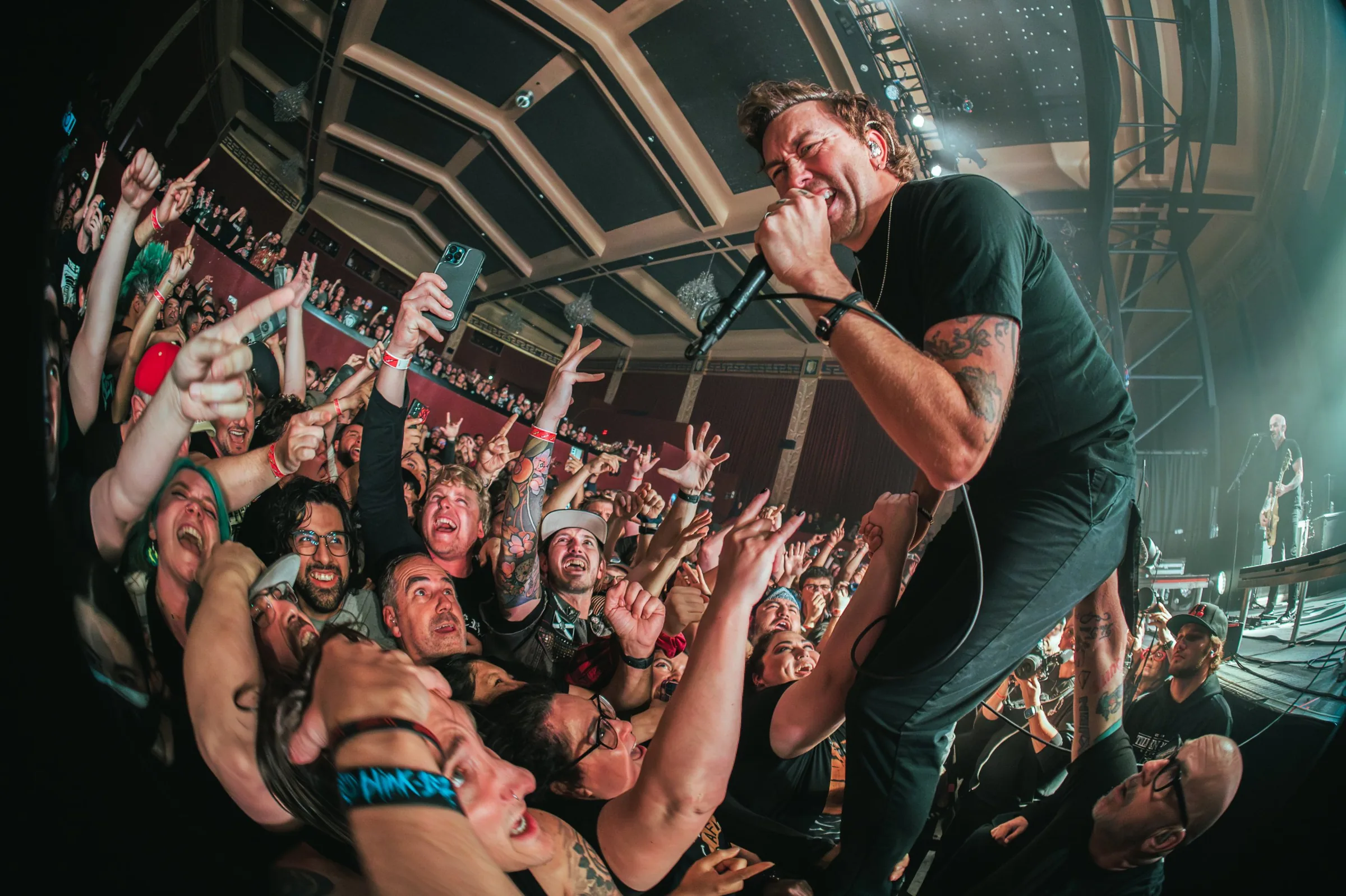 A singer leaning into a cheering crowd at The UC Theatre