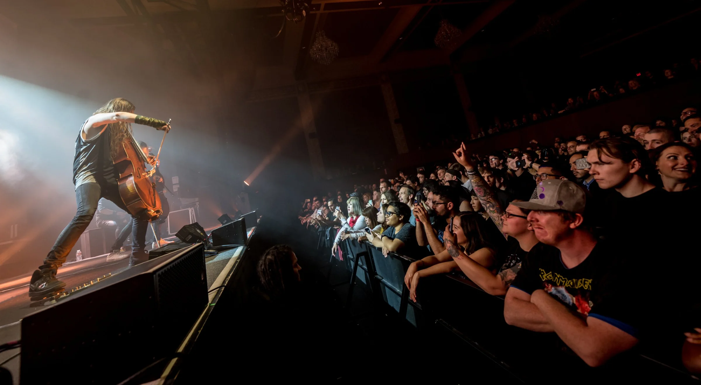 A cellist plays at the lip of the stage as the front rows cheer
