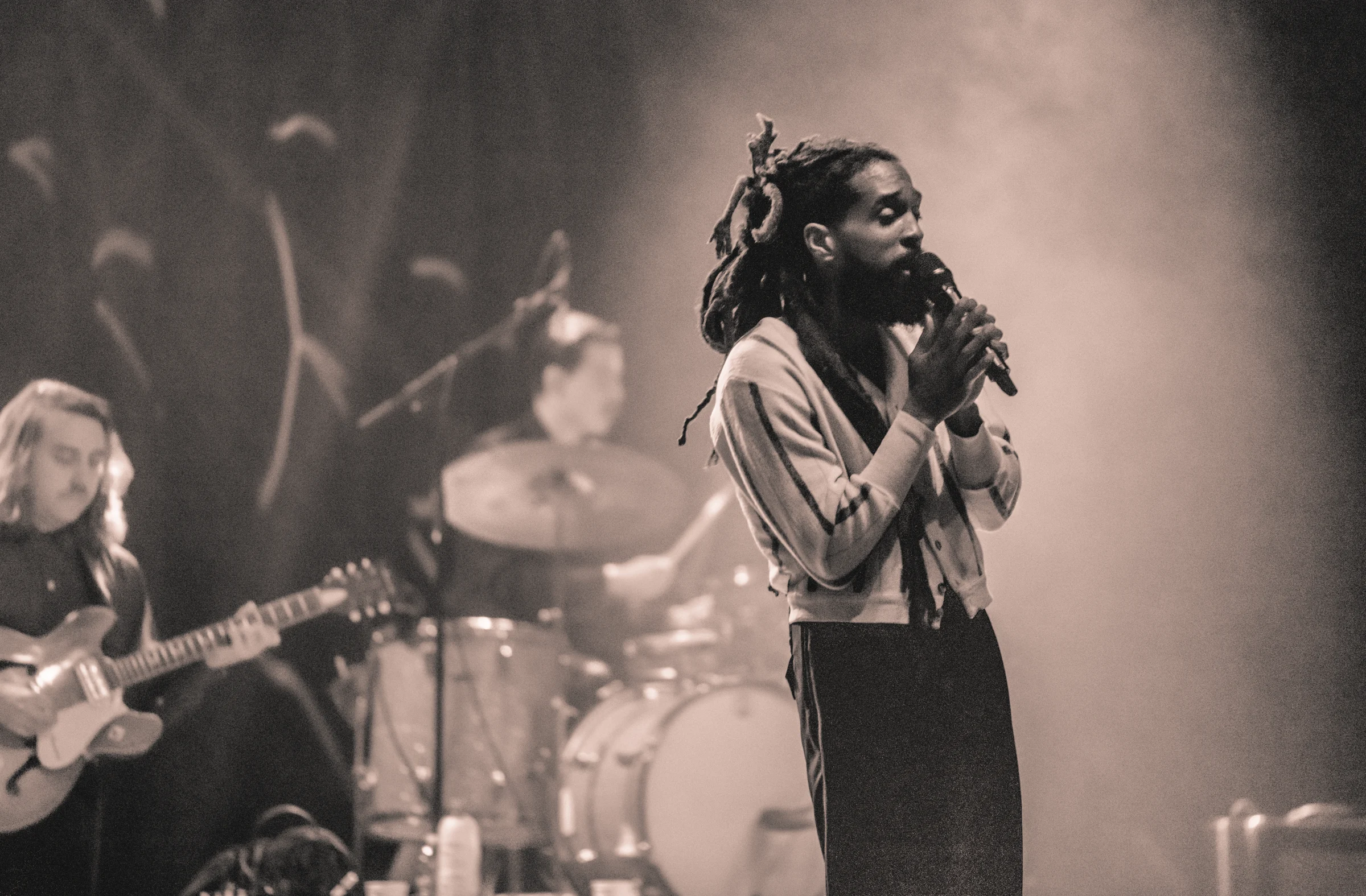 A singer holds the mic close in front of his band