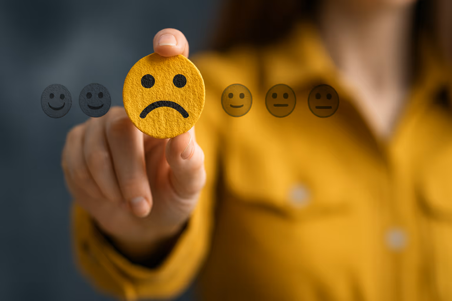 Customer selecting a sad face icon from a satisfaction scale, symbolizing loss of trust and confidence in data security.