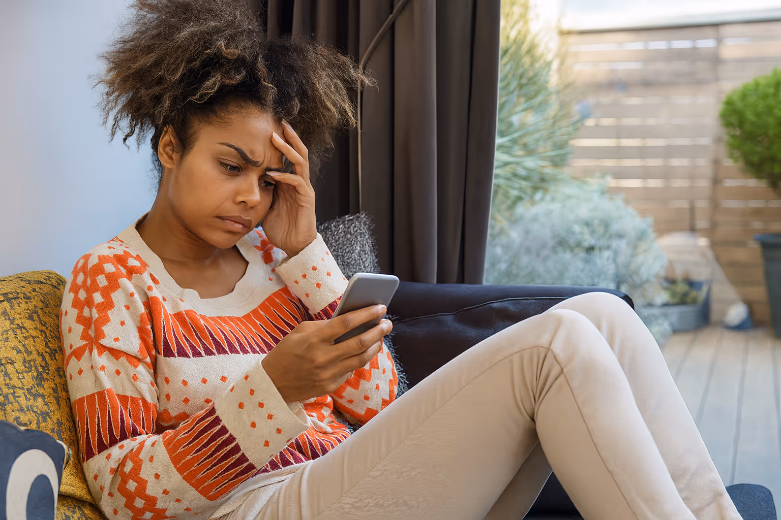 Woman looking stressed while checking her phone, symbolizing customer frustration with poor communication and disconnected experiences.