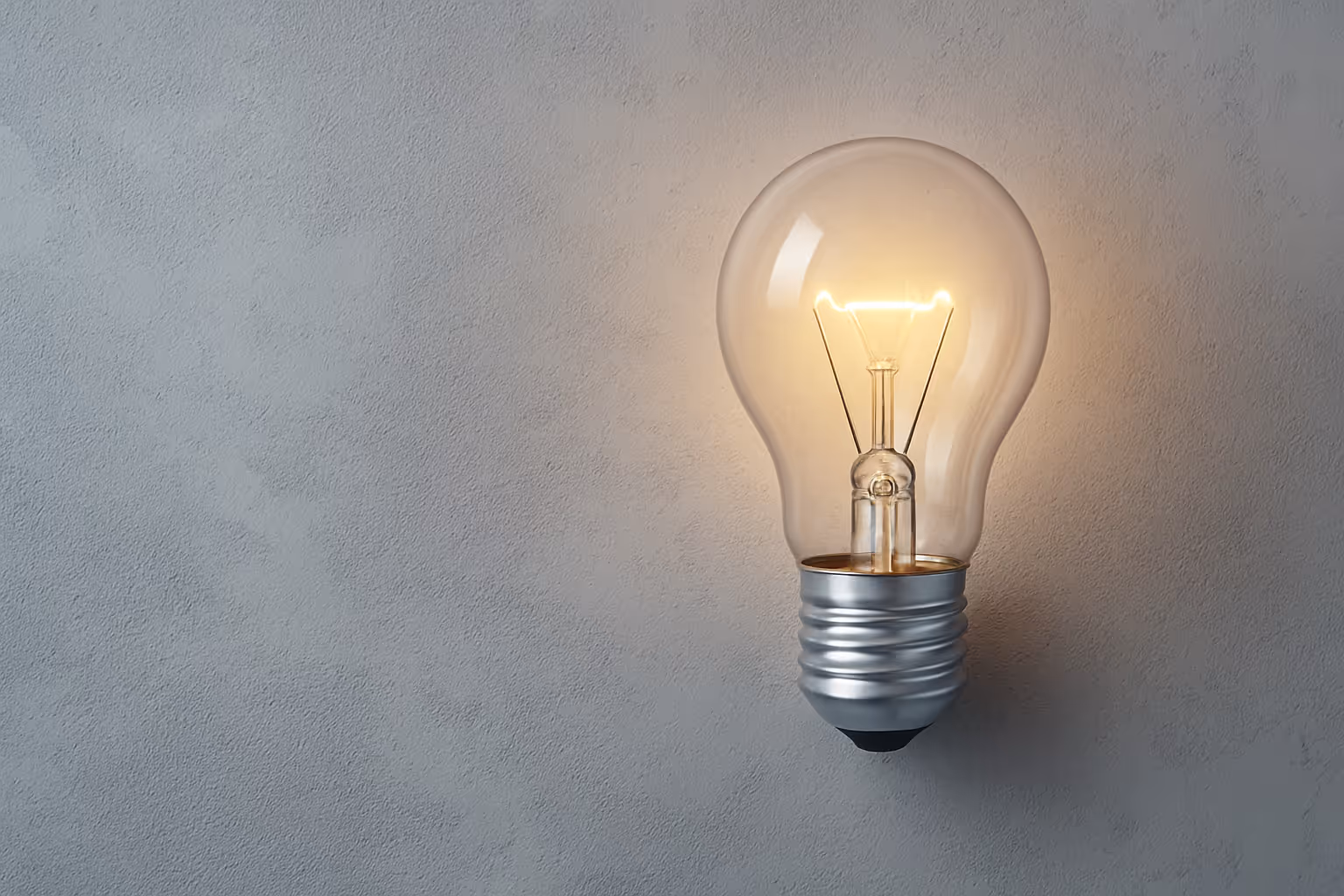 Glowing lightbulb on concrete background symbolizing ideas and clarity – Calder & Lane approach