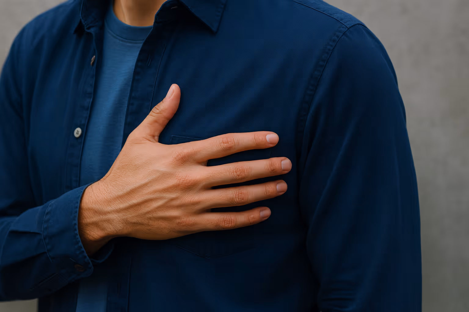 Close-up of a person’s hand placed over their heart, wearing a light blue shirt in natural light — symbolizing trust, authenticity, and integrity.
