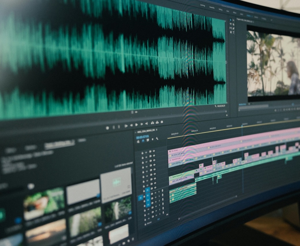 Computer screen displaying video editing software with audio waveforms and timeline tracks.