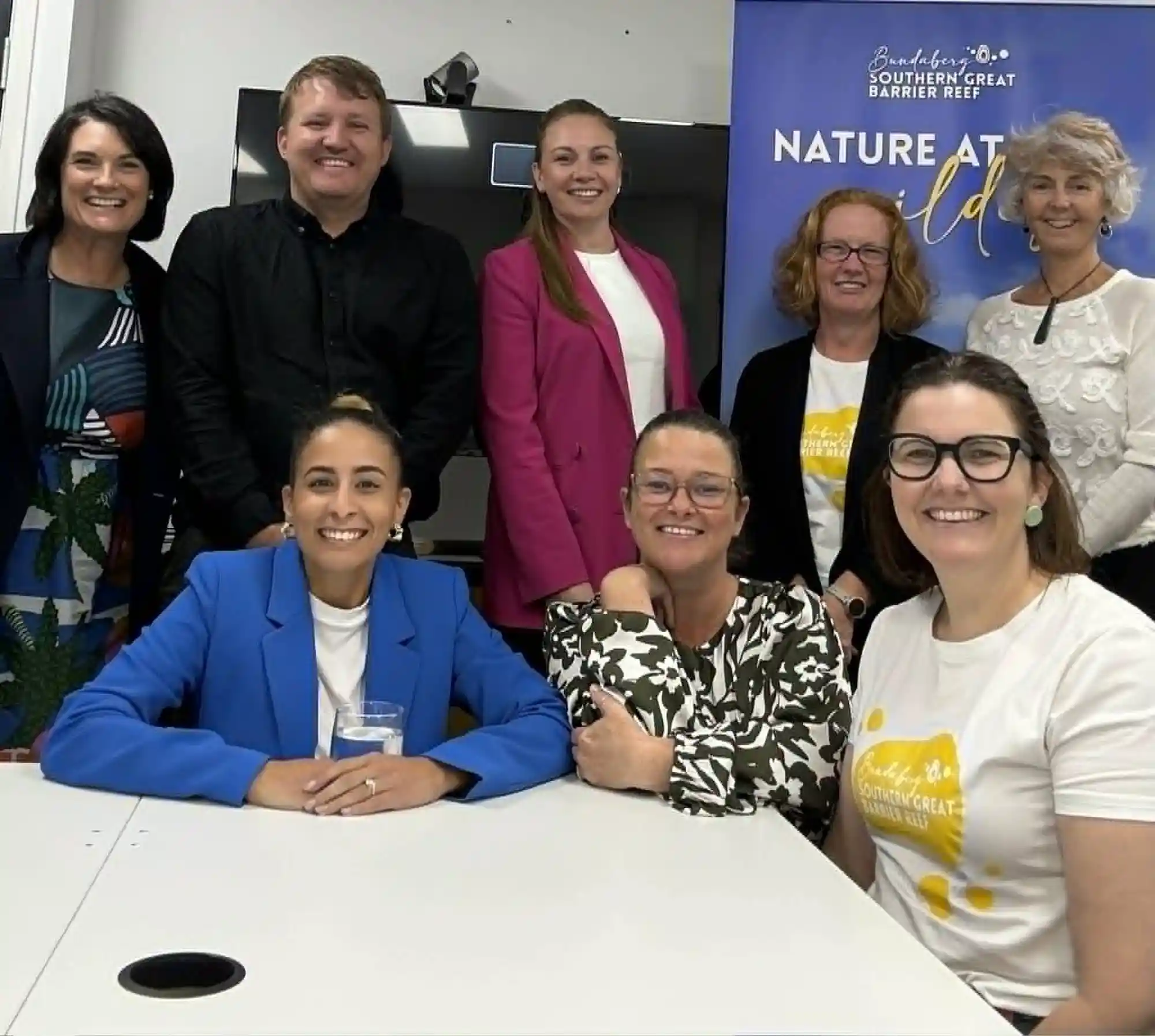 Nathan from Strategic Business Co in a group photo with the team from Bundaberg Tourism, in a meeting room with a Tourism Pull-Up Banner