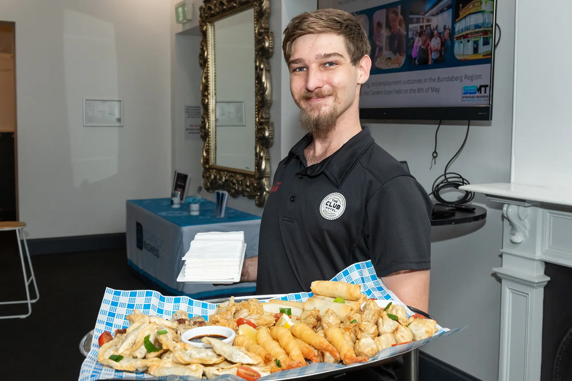 Bar staff member from the Club Hotel Bundaberg holding a platter of food at a Strategic Business Co event