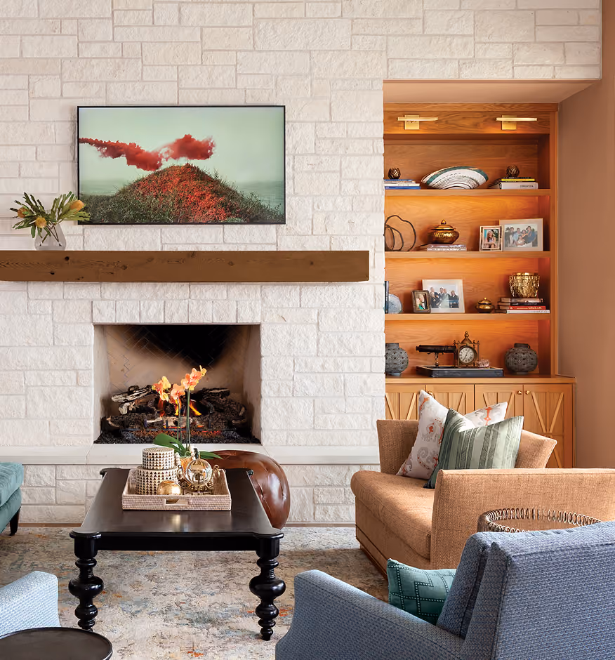 A modern living room with a white stone fireplace and armchairs