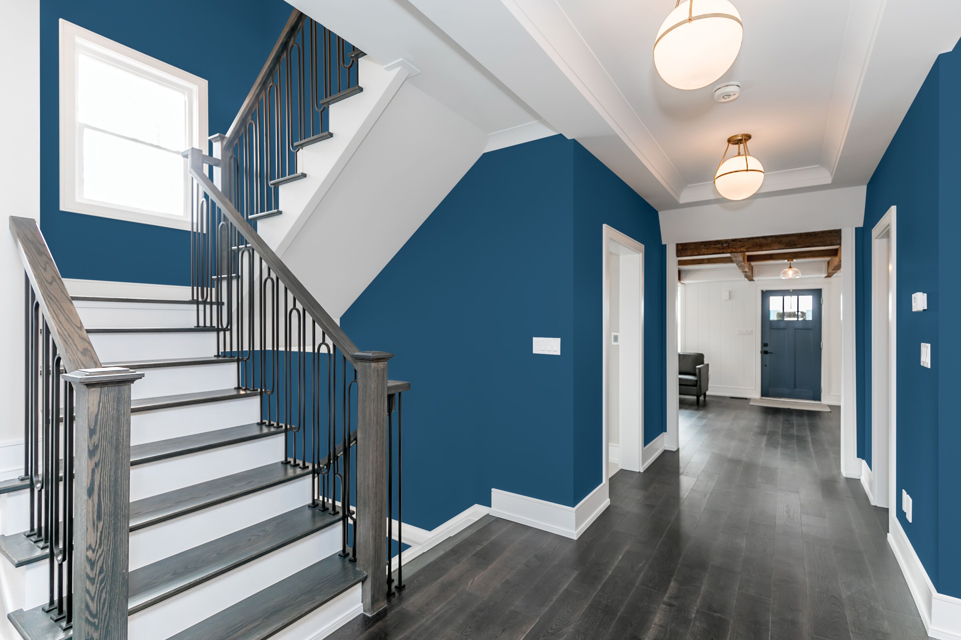 Bright home entryway and staircase with deep blue walls and white trim