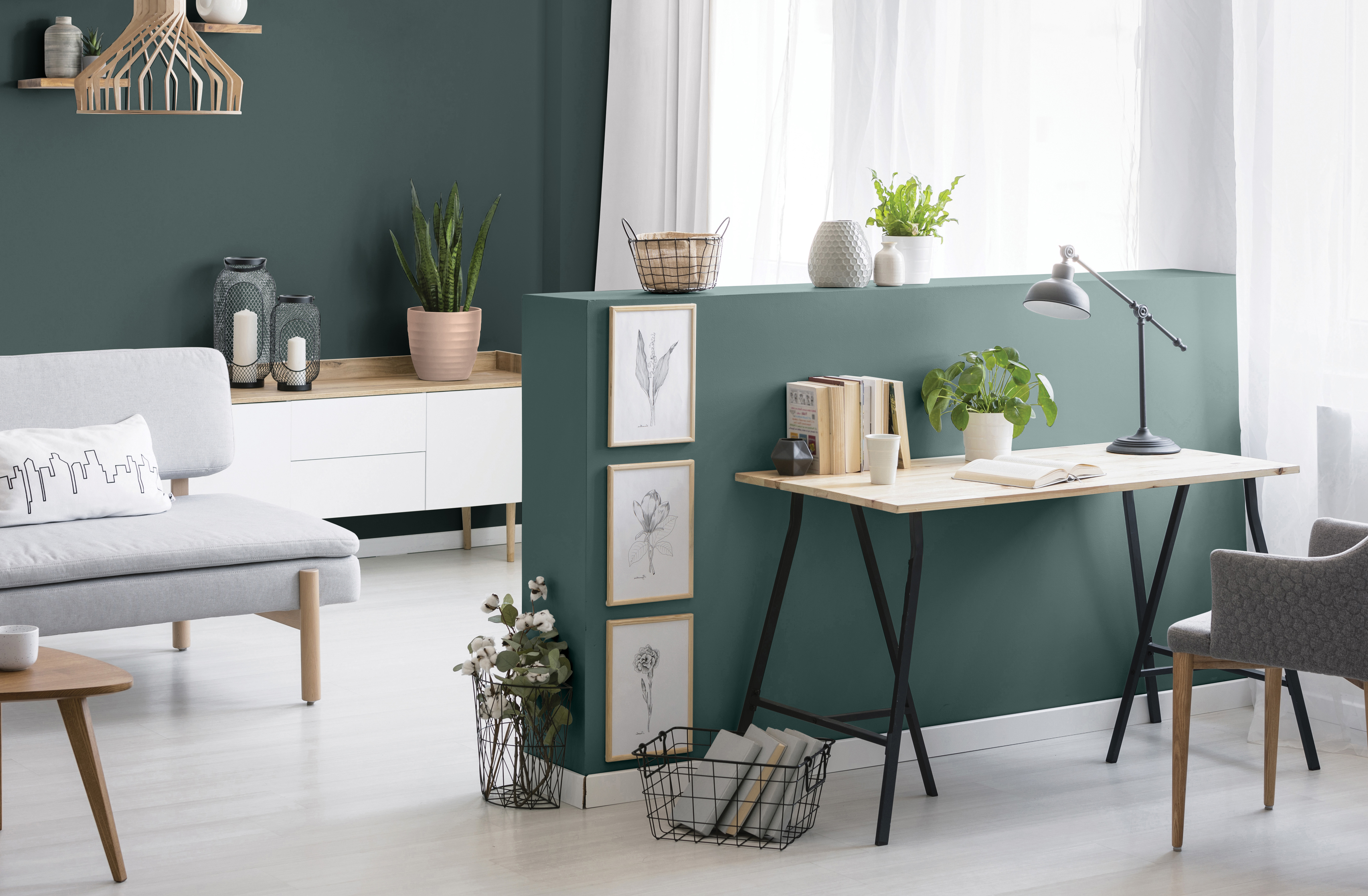 Open-plan living and workspace with deep forest green walls and minimalist furniture
