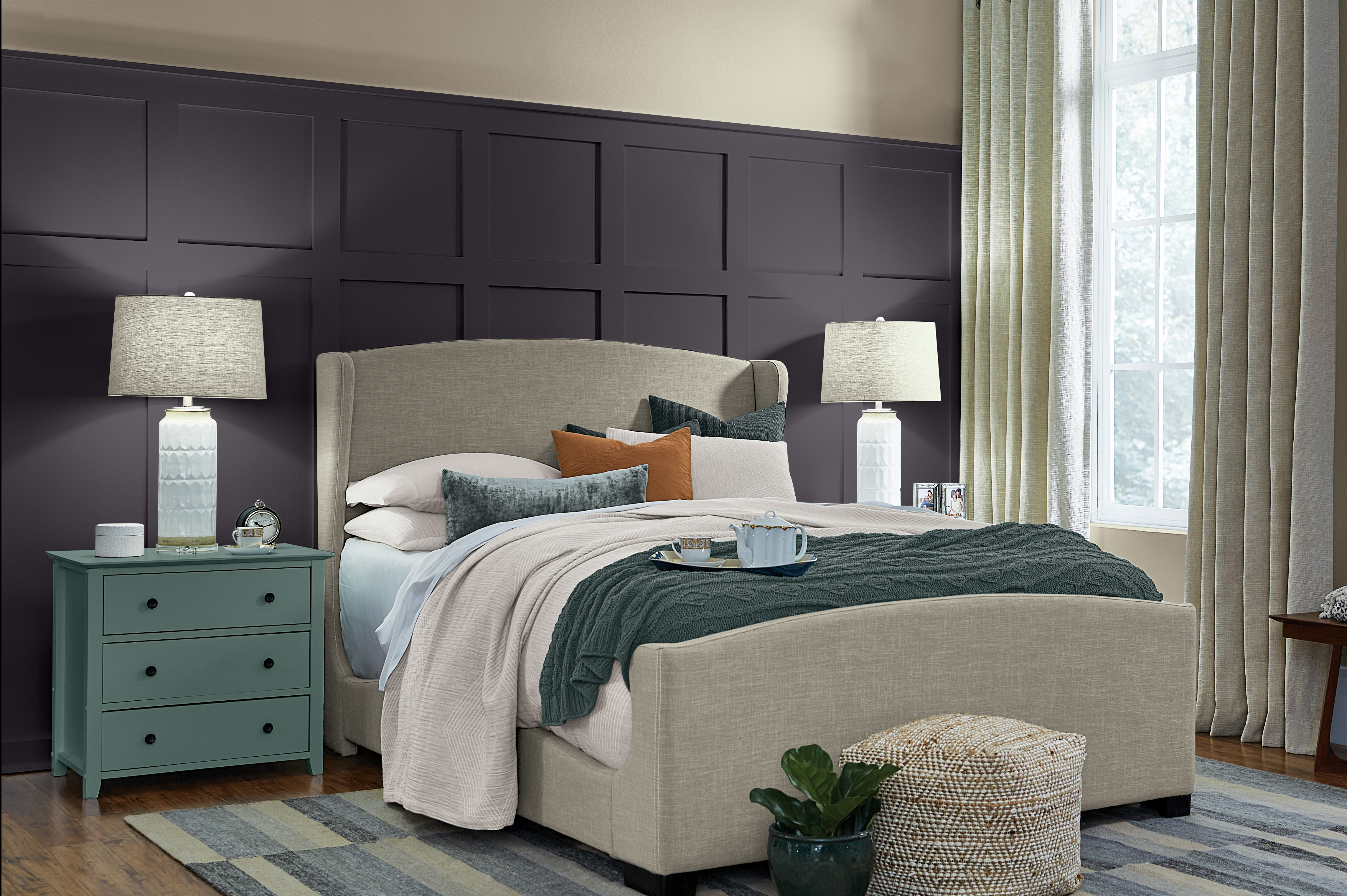 Modern bedroom with a dark grey accent wall and a beige upholstered bed