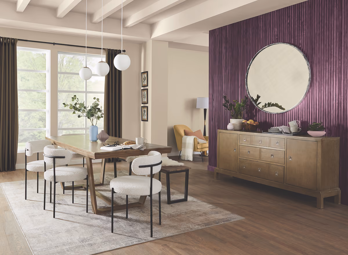 Elegant dining room with a deep purple accent wall, round mirror, and modern dining set