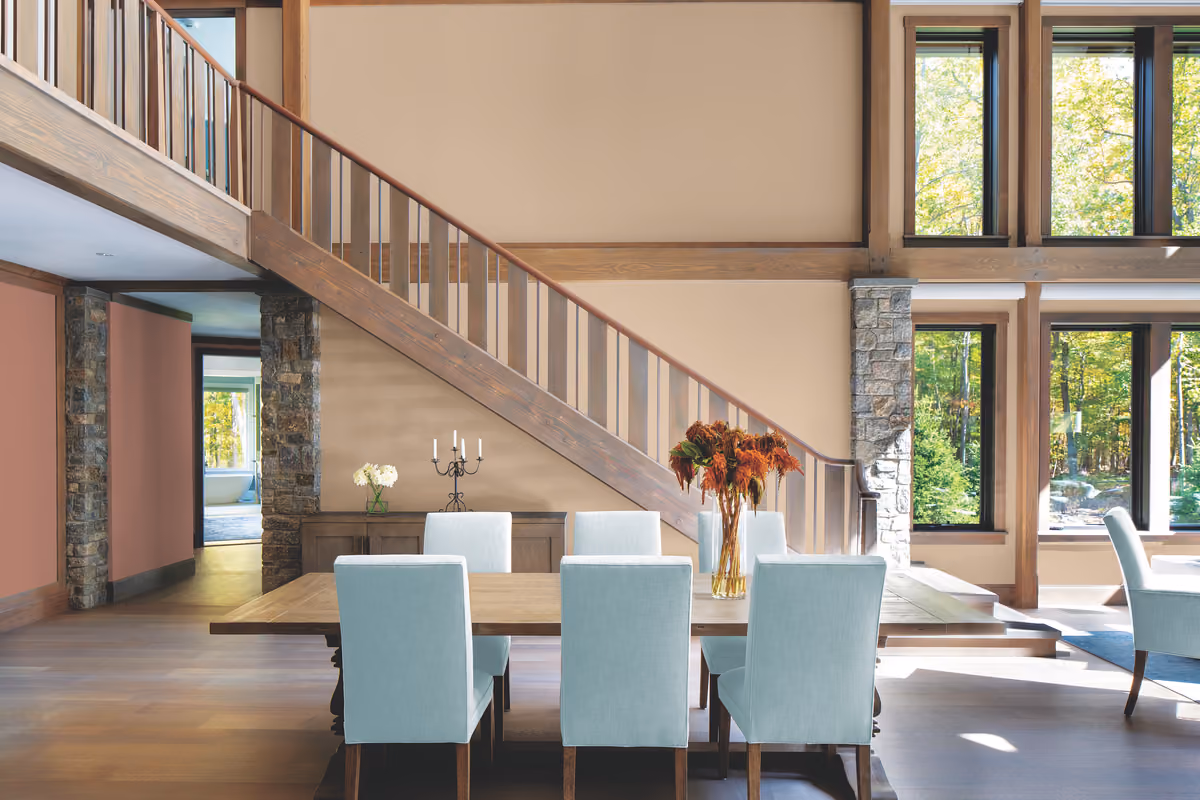 Spacious, open-concept dining area with a prominent wooden staircase and light blue chairs