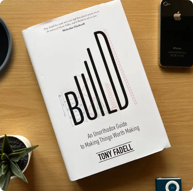 Build book by Tony Fadell on a desk next to other objects