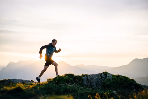 Man running through the mountains, focused on exercise and maintaining a healthy lifestyle in a scenic outdoor environment