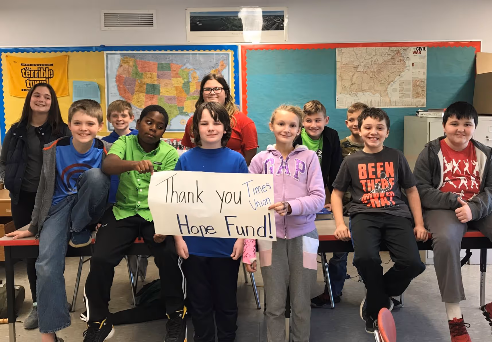 Group of students holding a sign that reads “Thank you Times Union Hope Fund!” in a classroom.