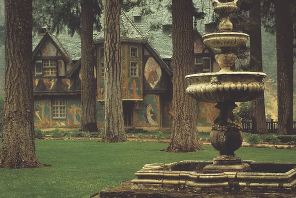 Exterior of Hearst’s family estate, “The Bear House,” in Wyntoon, California, featuring a fountain and wooded grounds.